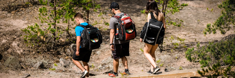 3 disc golfere går med tasker ned ad an trappe